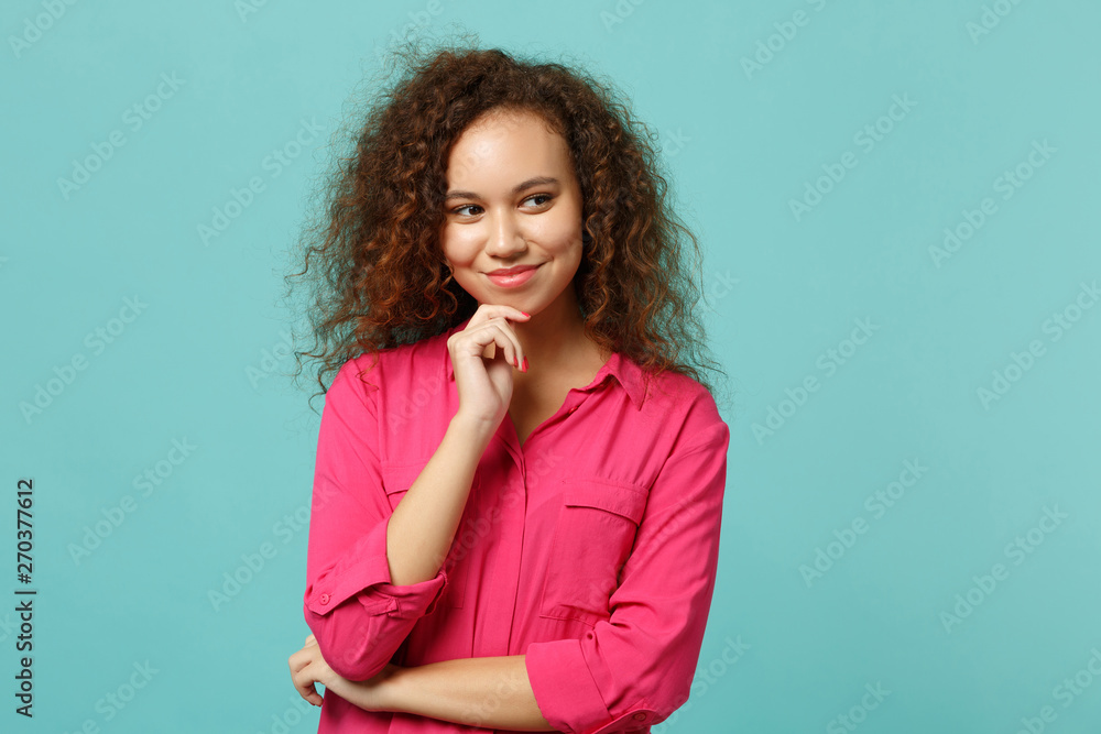 Smiling african american girl in casual clothes put hand prop up on chin looking aside isolated on blue turquoise background in studio. People sincere emotions, lifestyle concept. Mock up copy space. Smiling african american girl in casual clothes put hand prop up on chin looking aside isolated on blue turquoise background in studio. People sincere emotions, lifestyle concept. Mock up copy space.
