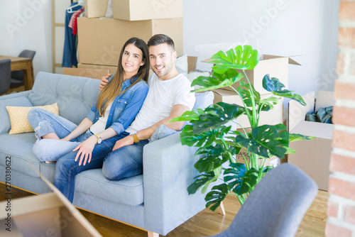 Young couple in love relaxing sitting on the sofa at new home, smiling happy for moving to new apartment