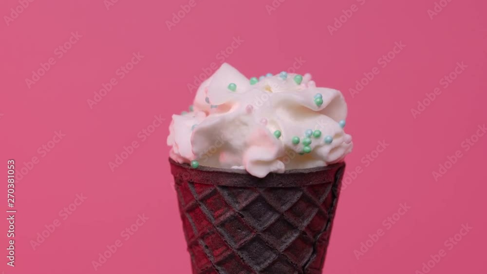 Soft ice cream in black cone decorated with colorful sprinkles over pink background Soft ice cream in black cone decorated with colorful sprinkles over pink background