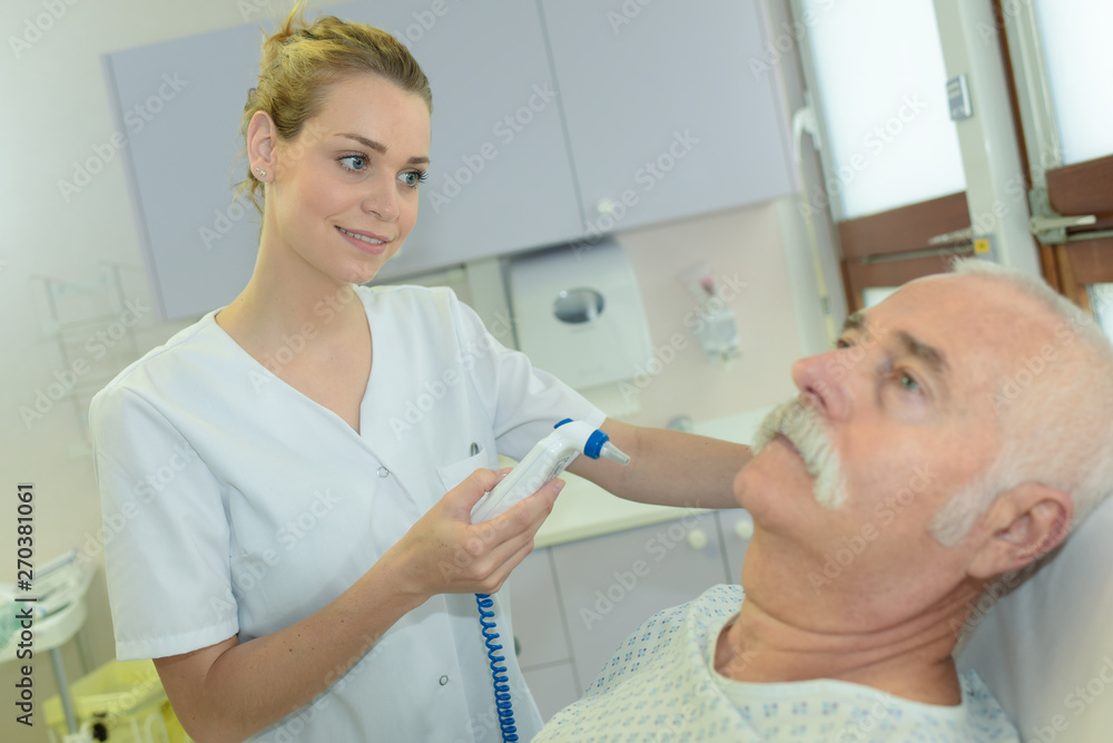 burse preparing to take senior patients temperature using ear instrument burse preparing to take senior patients temperature using ear instrument
