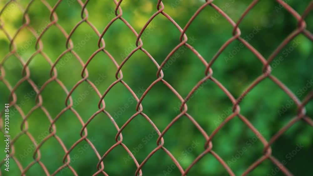 Close up pan of Rusted Metal Fencing looking at a blur of the woods. Close up pan of Rusted Metal Fencing looking at a blur of the woods.