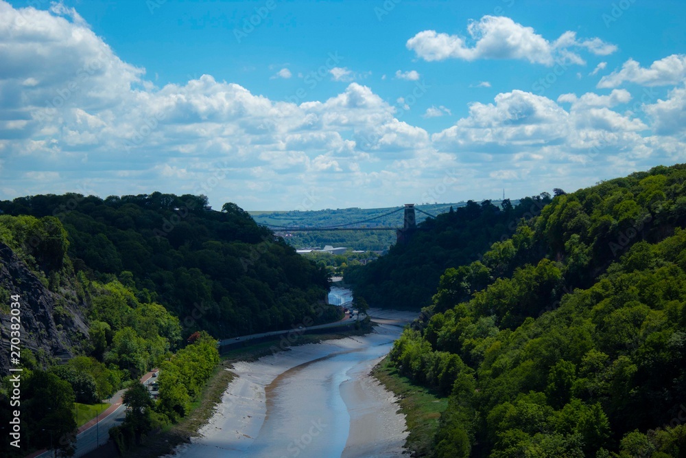 Avon gorge with the clifton suspension bridge in the background with vivid blue sky and white clouds and green forest