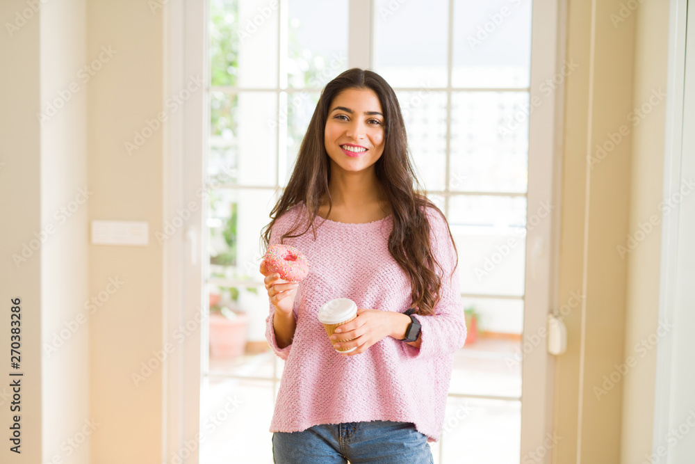 Young worker woman taking a break eating tasty pink donut and drinking a cup of coffee Young worker woman taking a break eating tasty pink donut and drinking a cup of coffee