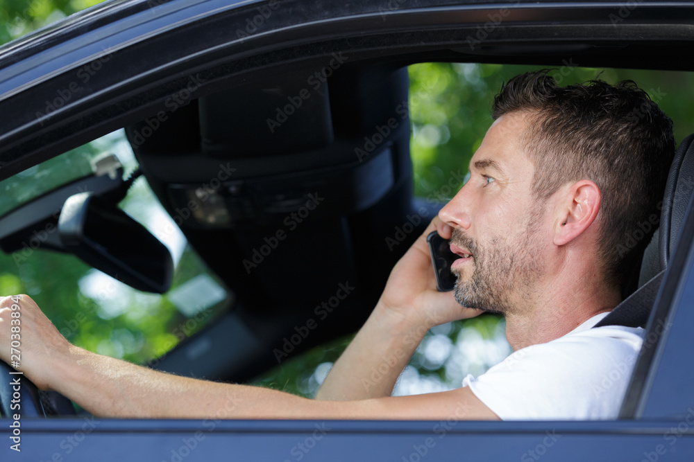 man driving car and using mobile phone