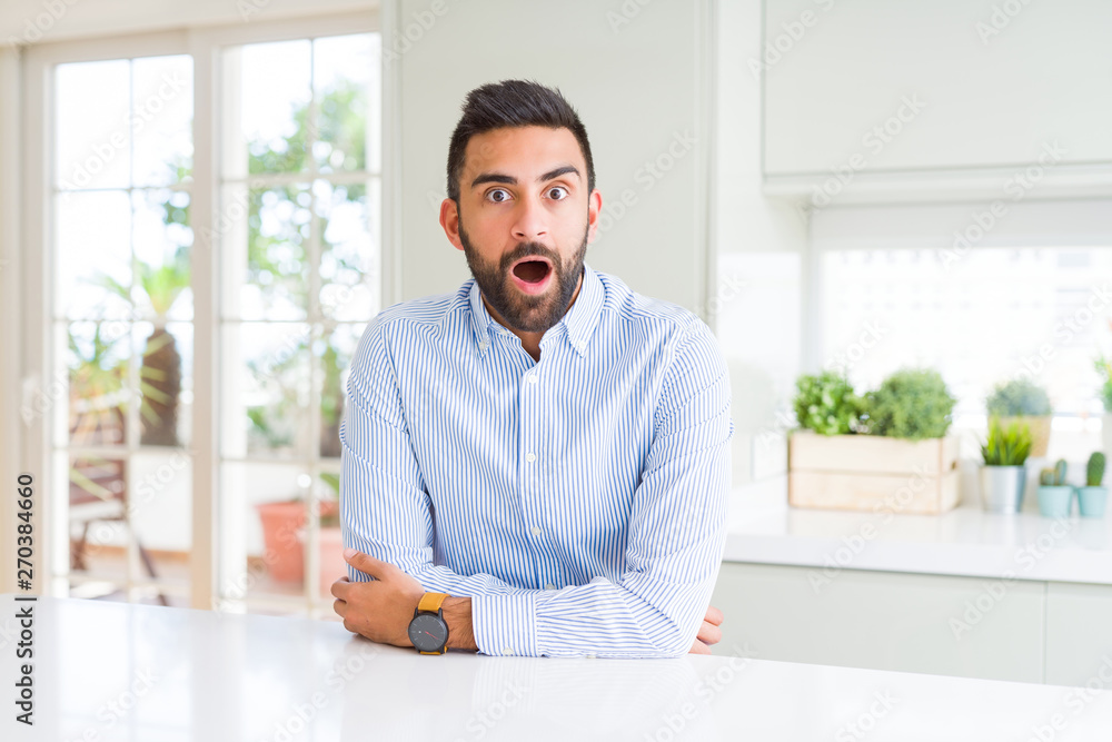 Handsome hispanic business man afraid and shocked with surprise expression, fear and excited face.