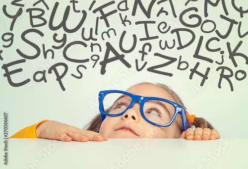 beautiful cute little girl looking at with handwritten letters of alphabet above her head
