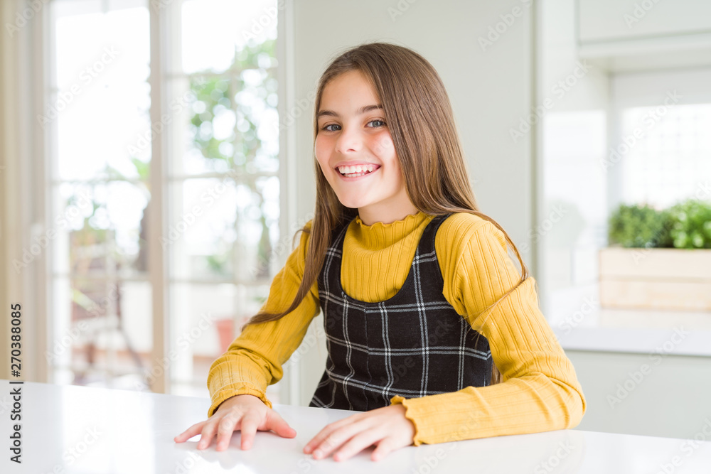 Young beautiful blonde kid girl wearing casual yellow sweater at home with a happy and cool smile on face. Lucky person.