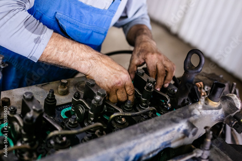 Mechanic repairs old motor of truck in a car repair station. Disassemble engine block vehicle. Motor capital repair. Car service concept