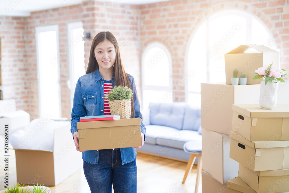 Beautiful asian young woman holding boxes, smiling happy moving to a new home Beautiful asian young woman holding boxes, smiling happy moving to a new home