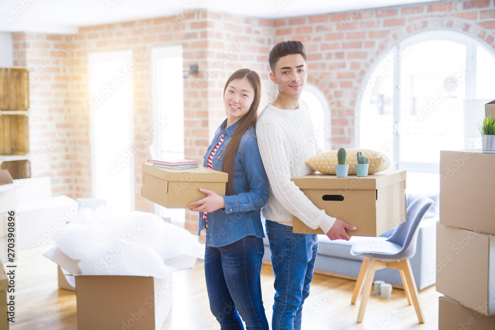 Beautiful young asian couple looking happy holding cardboard boxes, smiling excited moving to a new home Beautiful young asian couple looking happy holding cardboard boxes, smiling excited moving to a new home