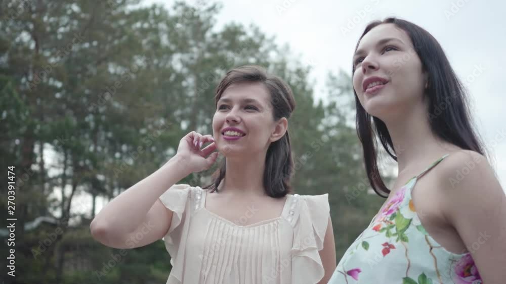Portrait two pretty smilling young women wear summer dresses standing in the top of rock and looking at amazing view of nature. Cute girls walk outside the city. Adorable girlfriends outdoors. Portrait two pretty smilling young women wear summer dresses standing in the top of rock and looking at amazing view of nature. Cute girls walk outside the city. Adorable girlfriends outdoors.