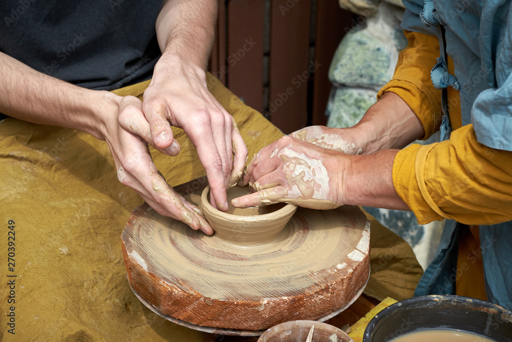 A closeup of a hand of two artisans making a jug