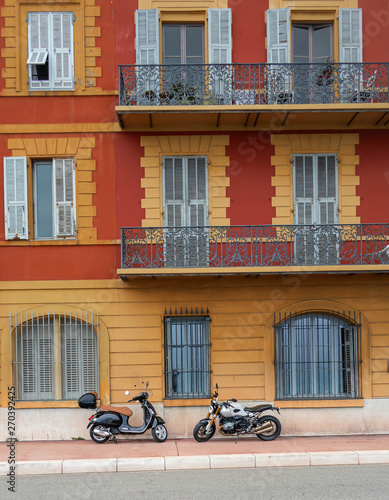 The scooter and the motorcycle against the background of the house with balconies.