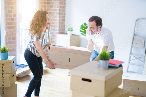 Middle age senior couple moving to a new house, holding cardboard boxing smiling happy in love with apartmant © Krakenimages.com