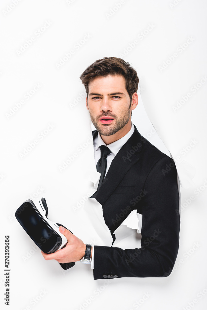 man in suit holding Virtual reality headset behind hole in wall on white man in suit holding Virtual reality headset behind hole in wall on white