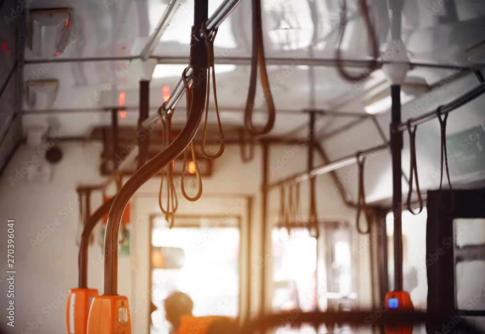 Travel around the city inside a public bus with black curved handrails illuminated by sunlight.