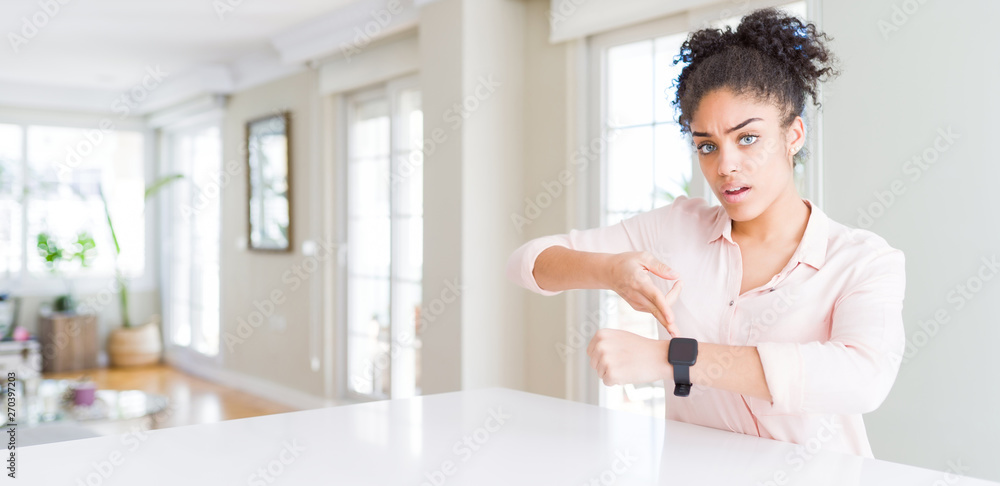 Wide angle of beautiful african american woman with afro hair In hurry pointing to watch time, impatience, upset and angry for deadline delay Wide angle of beautiful african american woman with afro hair In hurry pointing to watch time, impatience, upset and angry for deadline delay