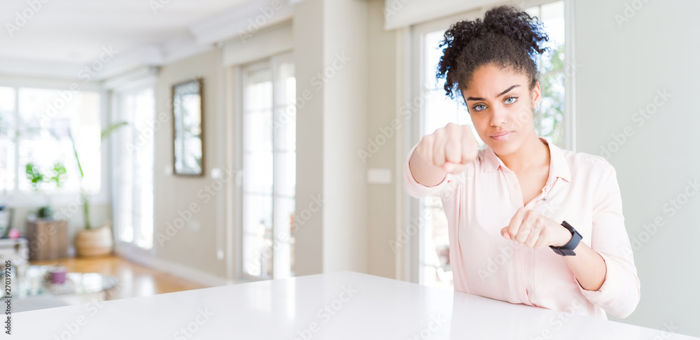 Wide angle of beautiful african american woman with afro hair Punching fist to fight, aggressive and angry attack, threat and violence Wide angle of beautiful african american woman with afro hair Punching fist to fight, aggressive and angry attack, threat and violence