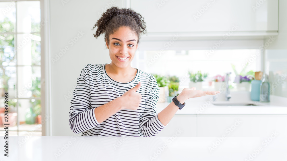Beautiful african american woman with afro hair wearing casual striped sweater Showing palm hand and doing ok gesture with thumbs up, smiling happy and cheerful Beautiful african american woman with afro hair wearing casual striped sweater Showing palm hand and doing ok gesture with thumbs up, smiling happy and cheerful