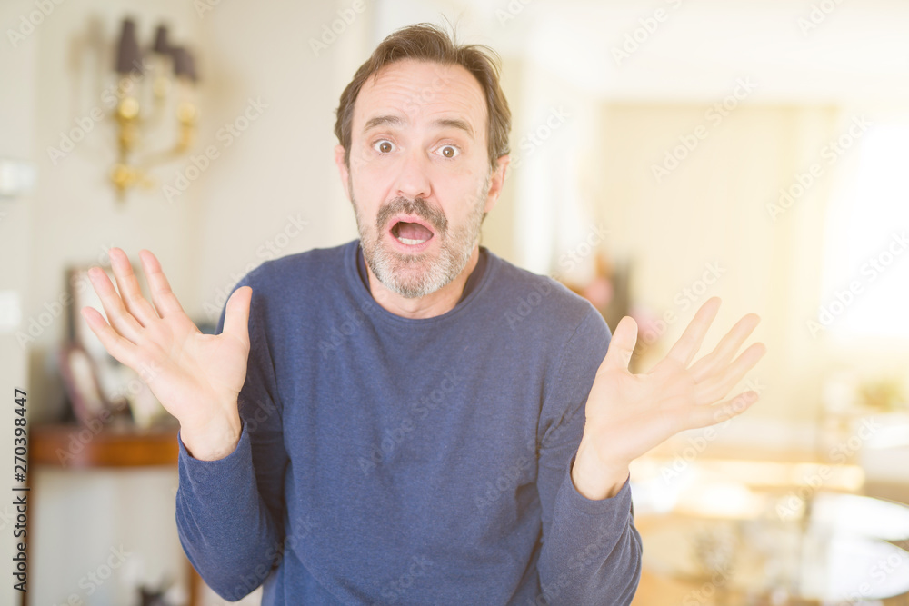 Handsome middle age man at home clueless and confused expression with arms and hands raised. Doubt concept. Handsome middle age man at home clueless and confused expression with arms and hands raised. Doubt concept.