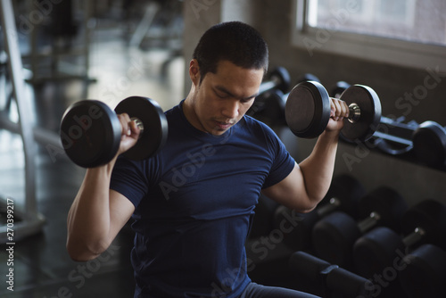 Young muscular lifting weights at gym