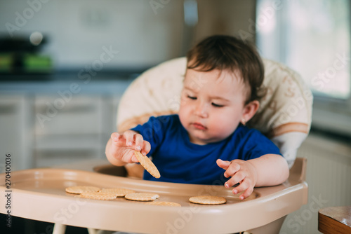 Little girl in a high chair eating round biscuits