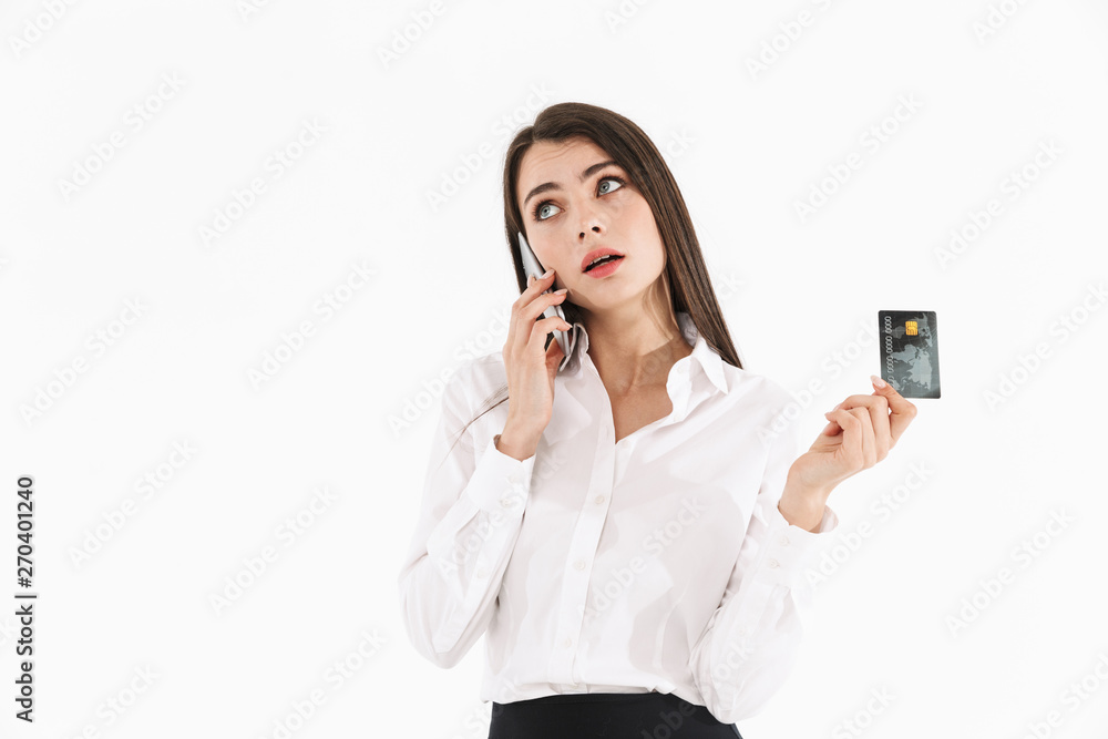 Photo of cheerful female worker businesswoman dressed in formal wear holding smartphone and credit card while working in office Photo of cheerful female worker businesswoman dressed in formal wear holding smartphone and credit card while working in office