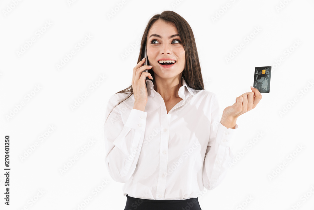 Photo of beautiful female worker businesswoman dressed in formal wear holding smartphone and credit card while working in office Photo of beautiful female worker businesswoman dressed in formal wear holding smartphone and credit card while working in office