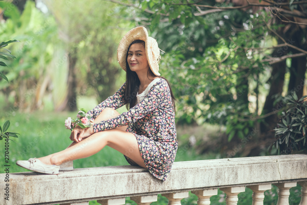 Naklejka premium Full Length Of Young Woman Sitting On Retaining Wall At Park