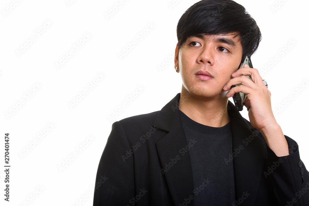 Studio shot of cool handsome Asian man talking on mobile phone w Studio shot of cool handsome Asian man talking on mobile phone w