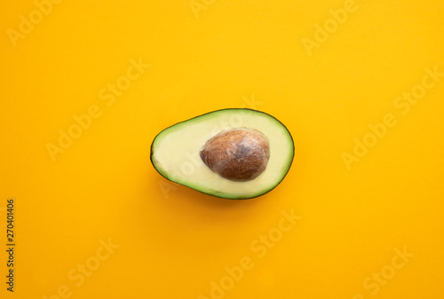 Close up ripe sliced avocado on bright yellow background top view flat lay. Tropical summer abstract background with avocado