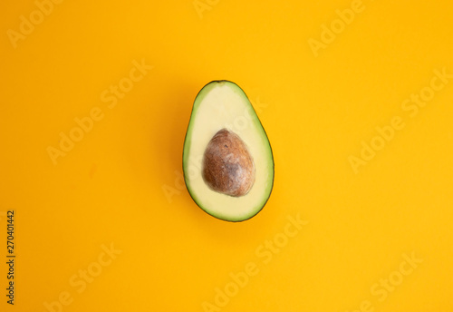Close up ripe sliced avocado on bright yellow background top view flat lay. Tropical summer abstract background with avocado