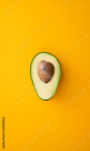 Close up ripe sliced avocado on bright yellow background top view flat lay. Tropical summer abstract background with avocado
