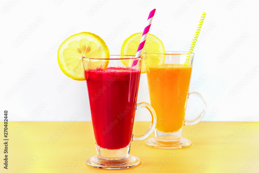 Two different colors cocktails in glass cups with straw and lemon slice. Healthy smoothies, white background. Two different colors cocktails in glass cups with straw and lemon slice. Healthy smoothies, white background.