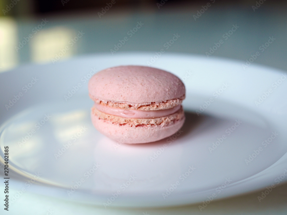 Rose flavored macaroon isolated on white plate. Selective focus.