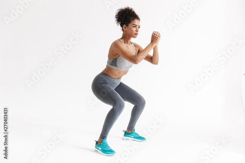 Amazing stronger sports fitness african woman make exercises isolated over white wall background.