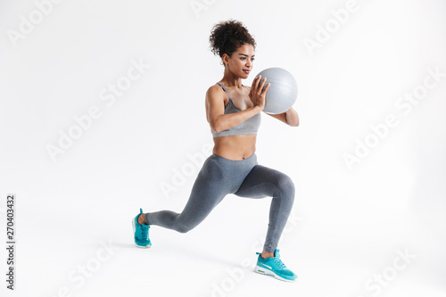 Young amazing sports fitness african woman posing isolated over white background make exercises with ball.