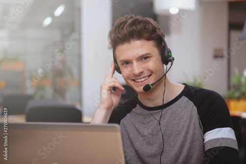 Fényképezés CHeerful handsome young man smiling to the camera, working at the call center, copy space