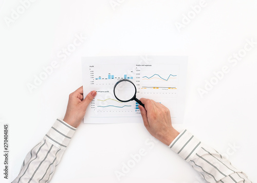 Woman's hands are reviewing a report with graphs on a white table. Minimalistic concept Finance and business.