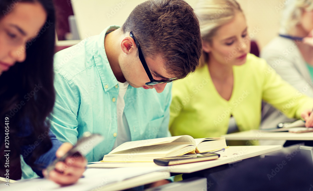 education, high school, university, learning and people concept - male student in glasses reading book at lecture education, high school, university, learning and people concept - male student in glasses reading book at lecture