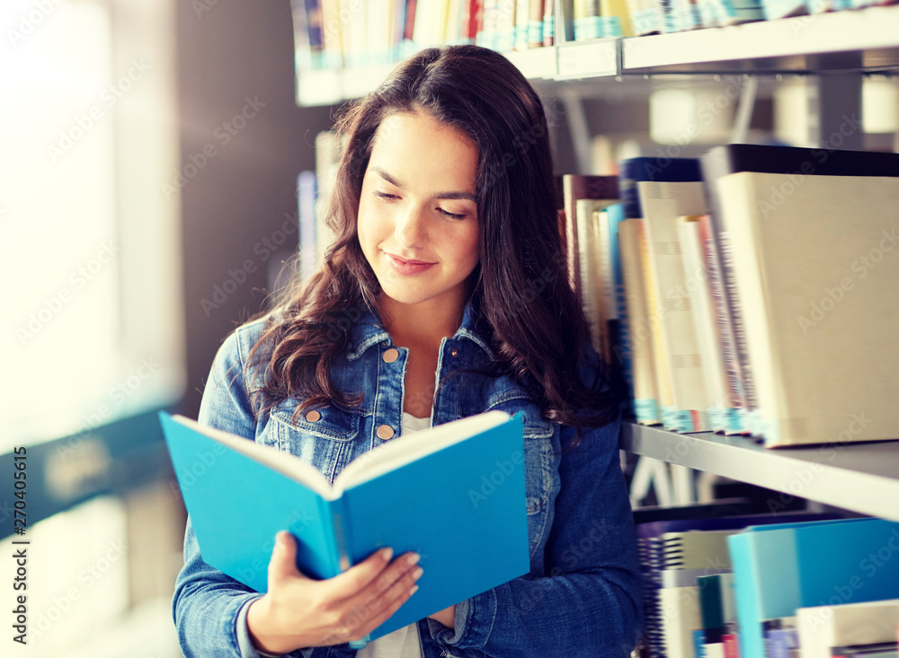 education, high school, university, learning and people concept - smiling student girl reading book at library education, high school, university, learning and people concept - smiling student girl reading book at library