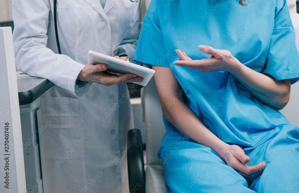 partial view of doctor in white coat showing digital tablet with diagnosis to patient partial view of doctor in white coat showing digital tablet with diagnosis to patient