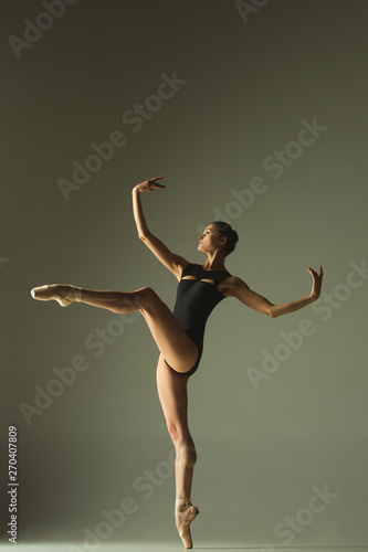 Graceful ballet dancer or classic ballerina dancing isolated on grey studio background. Showing flexibility and grace. The dance, artist, contemporary, movement, action and motion concept.