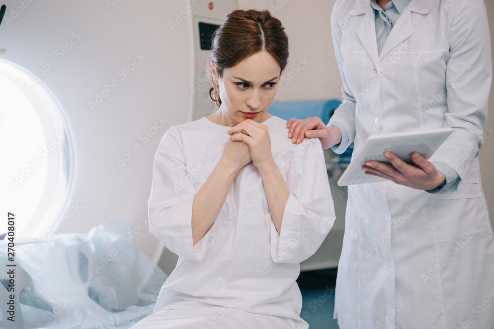 partial view of radiologist showing digital tablet with x-ray diagnosis to worried patient partial view of radiologist showing digital tablet with x-ray diagnosis to worried patient