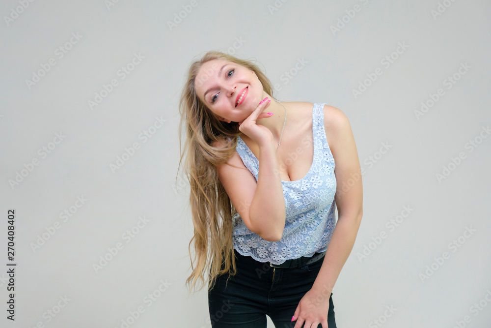 Naklejka premium Life is beautiful and I like everything here. I am satisfied with life and I wish you. Portrait of a smiling beautiful blonde girl on a gray background in various poses.
