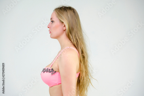 I have a beautiful figure and a long hair. I want to be a model. Look at me - am I really good? Portrait of a blonde model on a white background in bathing suit. She stands straight