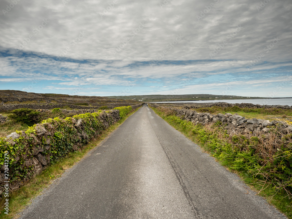 Small asphalt road, dry stone walls, cloudy day, Inismore, Aran islands, Ireland.