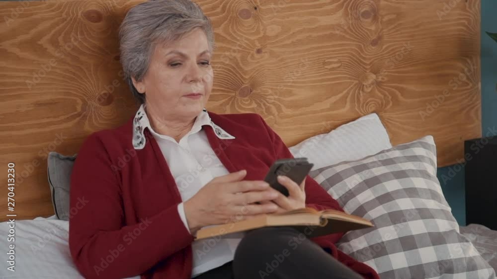 Senior woman is reading book but then interrupted by phone call from family. Senior woman is reading book but then interrupted by phone call from family.