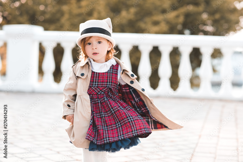 Stylish kid girl 1-2 year old wearing dress and jacket over city background  closeup. Looking at camera. Childhood. Stock Photo