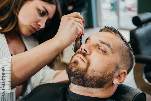 the barber cuts his beard to a brutal man in the salon